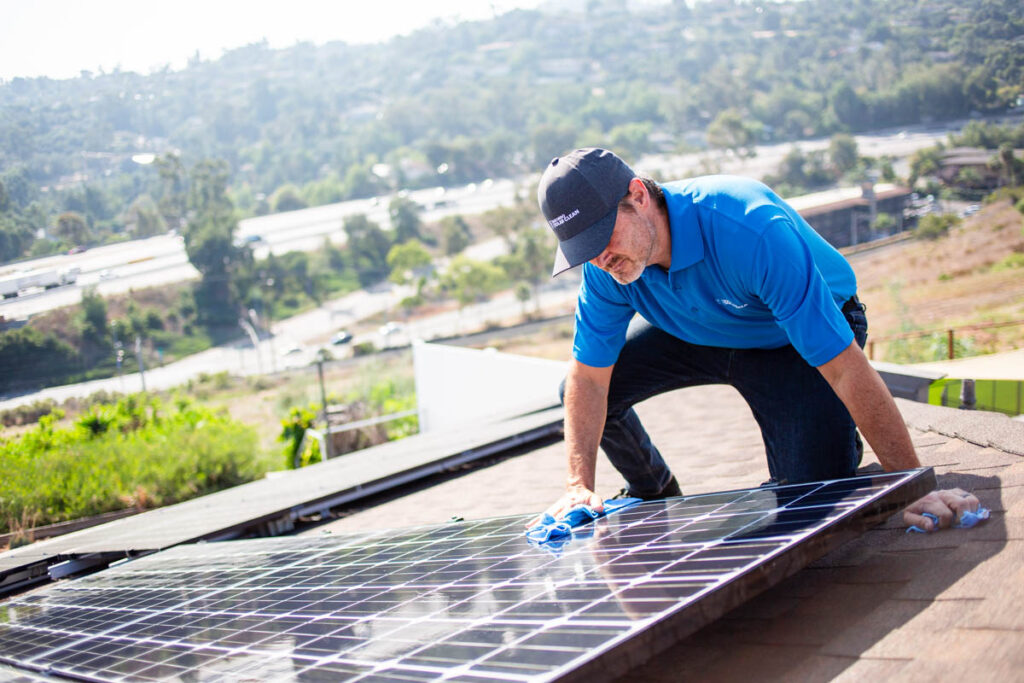 a guy wiping down a solar panel